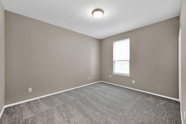 carpeted empty room featuring baseboards