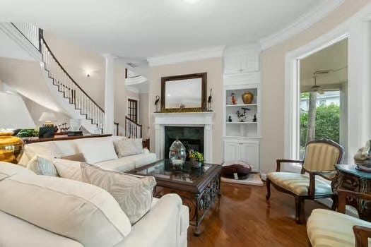 2 Argonne Pl, The Woodlands, TX 77382 - living area featuring stairs, wood finished floors, a fireplace, crown molding, and built in shelves