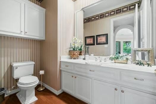 2 Argonne Pl, The Woodlands, TX 77382 - half bathroom with toilet, wallpapered walls, vanity, wood finished floors, and baseboards