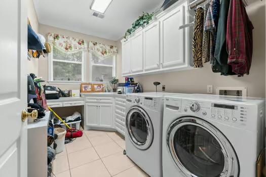 2 Argonne Pl, The Woodlands, TX 77382 - laundry room featuring washer and clothes dryer, cabinet space, and light tile patterned flooring
