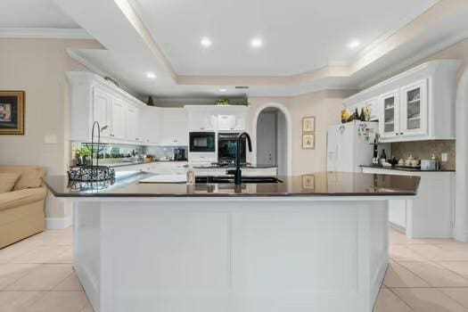 2 Argonne Pl, The Woodlands, TX 77382 - kitchen featuring freestanding refrigerator, light tile patterned floors, black microwave, white cabinets, and ornamental molding