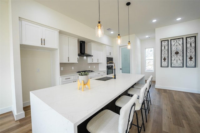 4111 Dreyfus St, Houston, TX 77021 - kitchen featuring wall chimney range hood, stainless steel gas stovetop, white cabinets, wood finished floors, and recessed lighting