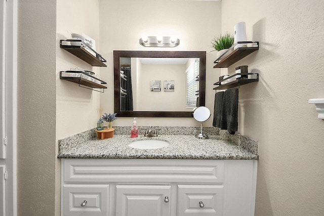 bathroom featuring vanity and a textured wall