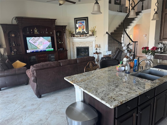 24130 Cannon Anello Ct, Katy, TX 77493 - kitchen featuring a sink, open floor plan, ceiling fan, light stone countertops, and a glass covered fireplace
