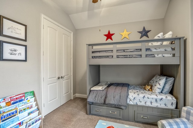 bedroom with carpet floors, lofted ceiling, a closet, and baseboards