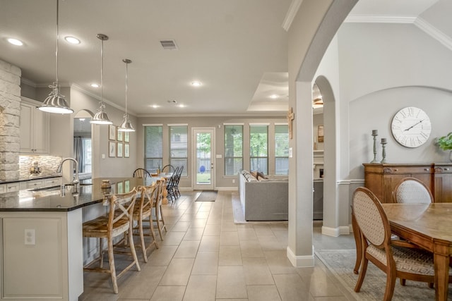 dining space with arched walkways, recessed lighting, crown molding, light tile patterned floors, and baseboards