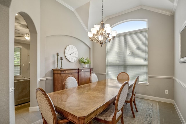 tiled dining area featuring a chandelier, plenty of natural light, lofted ceiling, arched walkways, and a ceiling fan