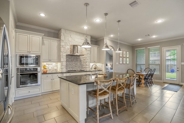 kitchen with appliances with stainless steel finishes, a sink, wall chimney range hood, light tile patterned floors, and recessed lighting