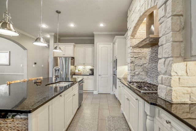 kitchen featuring stainless steel appliances, a sink, wall chimney range hood, ornamental molding, and decorative backsplash