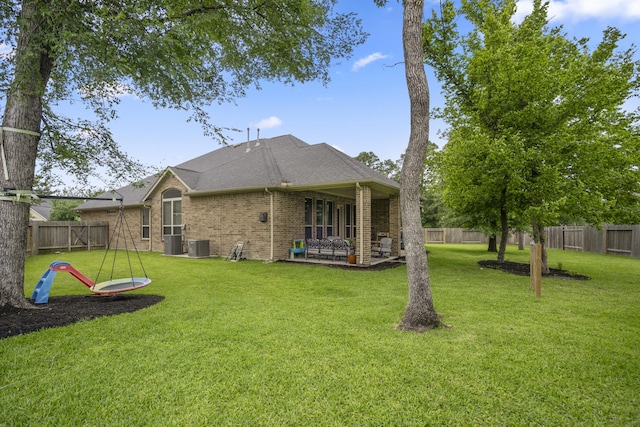 rear view of property with brick siding, a patio area, central AC unit, and a shingled roof