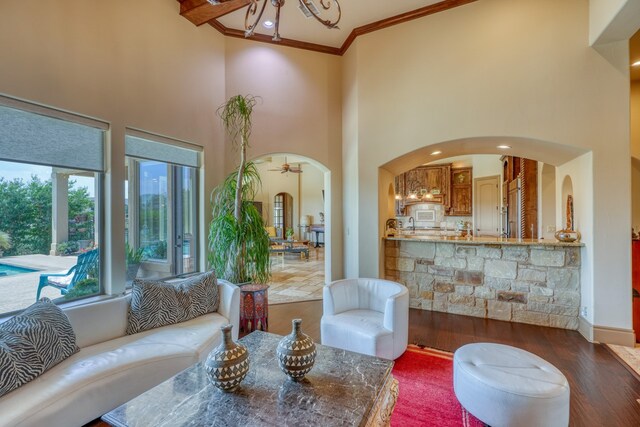 143 Westgate Loop, Horseshoe Bay, TX 78657 - living area featuring arched walkways, ornamental molding, a high ceiling, dark wood-style flooring, and a chandelier