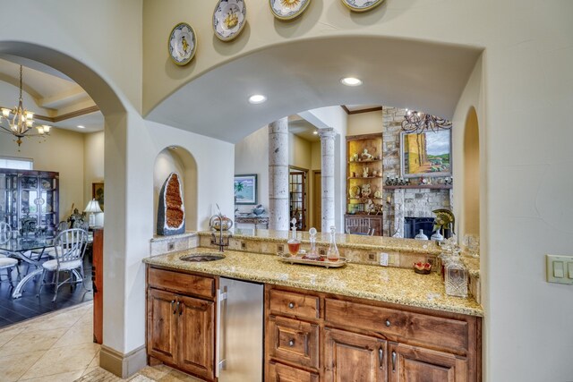 143 Westgate Loop, Horseshoe Bay, TX 78657 - bar featuring a sink, refrigerator, a chandelier, hanging light fixtures, and a fireplace