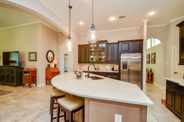 1523 Cafe Dumonde, Conroe, TX 77304 - kitchen with stainless steel fridge, a sink, decorative backsplash, a breakfast bar area, and dark brown cabinetry