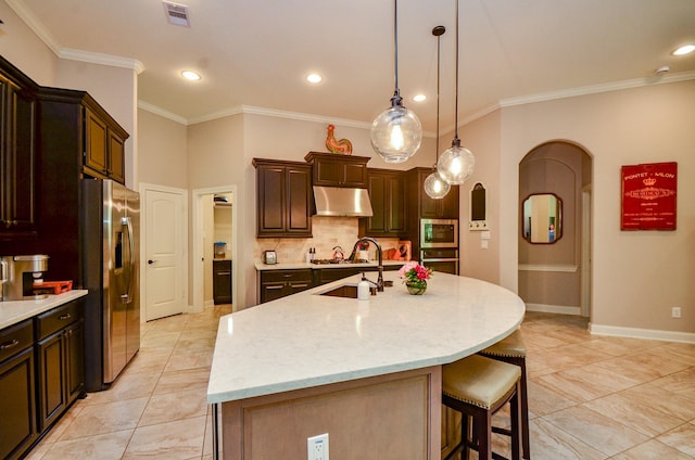 1523 Cafe Dumonde, Conroe, TX 77304 - kitchen with stainless steel appliances, under cabinet range hood, arched walkways, backsplash, and a sink