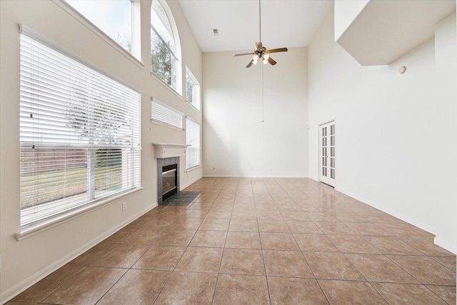 15027 Moss Bridge Ln, Sugar Land, TX 77498 - unfurnished living room with ceiling fan, a premium fireplace, a towering ceiling, plenty of natural light, and tile patterned flooring