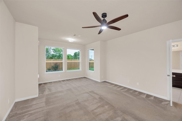 empty room with carpet floors, a ceiling fan, and baseboards