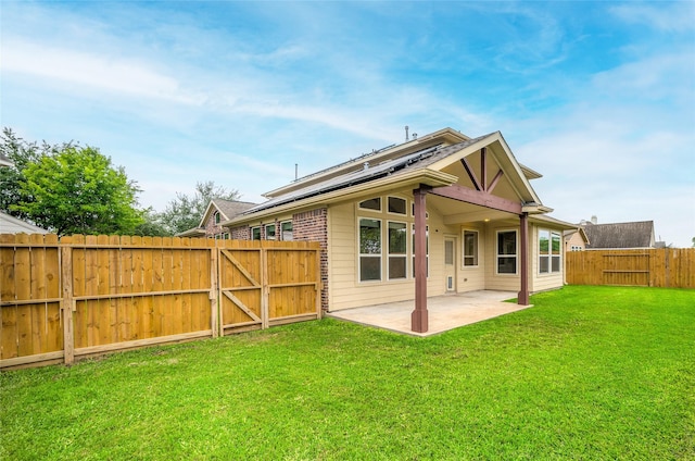 rear view of house featuring a gate, roof mounted solar panels, and a patio