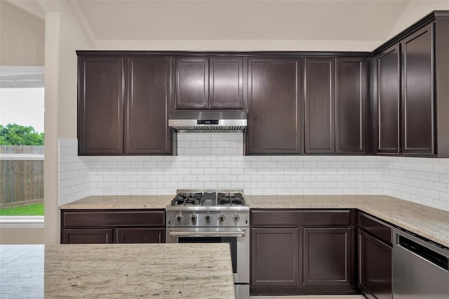 kitchen featuring stainless steel appliances, under cabinet range hood, dark brown cabinetry, tasteful backsplash, and light stone countertops