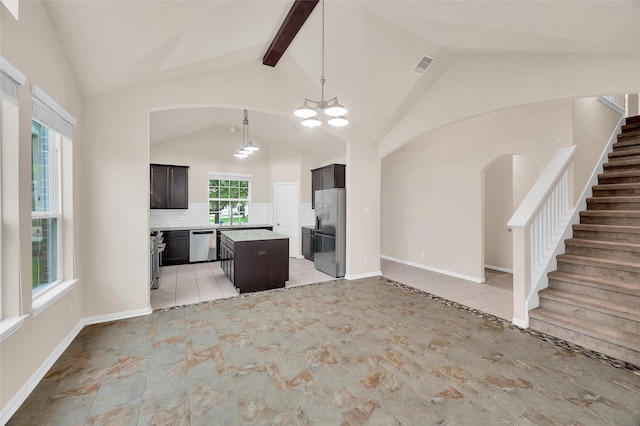 kitchen featuring stainless steel appliances, a kitchen island, open floor plan, a chandelier, and decorative backsplash