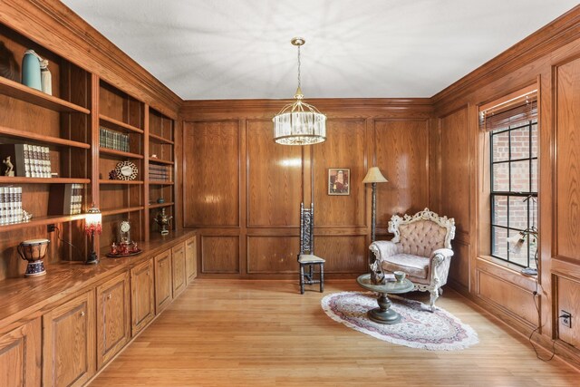 living area featuring a chandelier, light wood-type flooring, and wooden walls