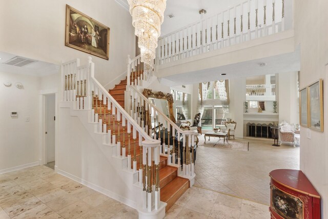 stairs featuring a high ceiling, a chandelier, and baseboards