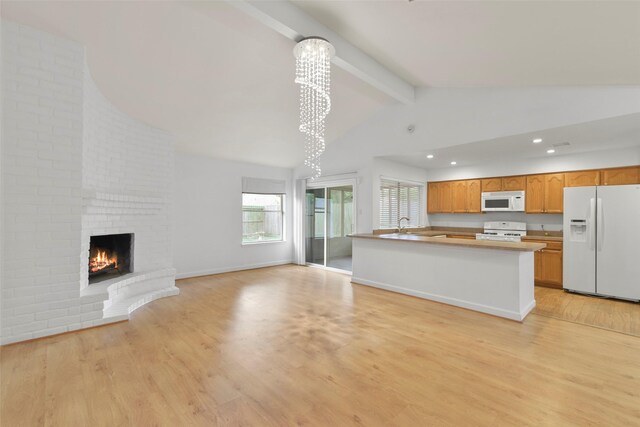 kitchen featuring white appliances, open floor plan, a chandelier, light wood finished floors, and a brick fireplace