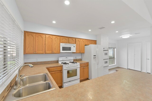 kitchen featuring white appliances, a sink, light countertops, and recessed lighting