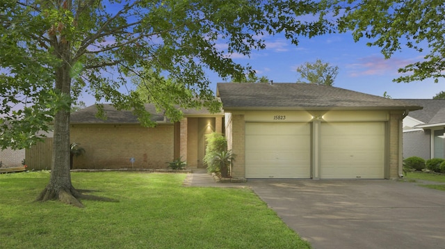 view of front facade with a garage, driveway, brick siding, a front yard, and roof with shingles