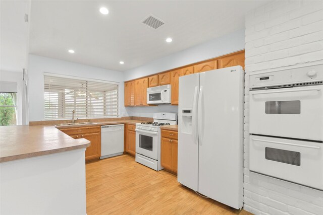 kitchen featuring white appliances, a sink, healthy amount of natural light, light wood-type flooring, and recessed lighting