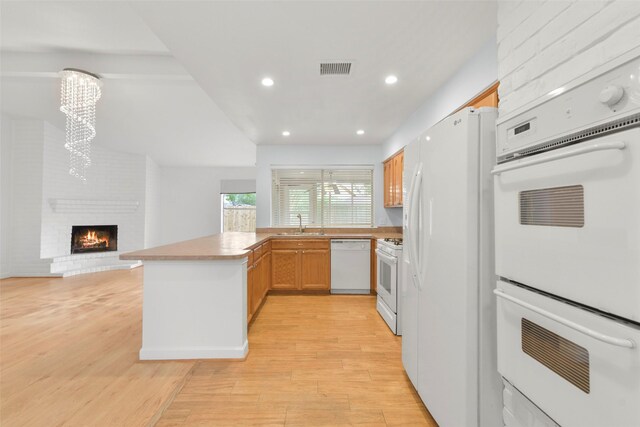 kitchen with white appliances, a chandelier, a peninsula, light countertops, and recessed lighting