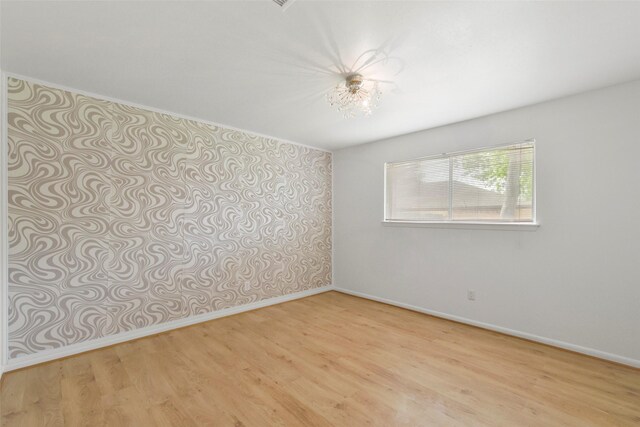 spare room featuring light wood-style floors and baseboards