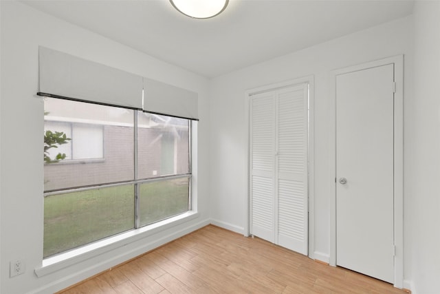 unfurnished bedroom featuring wood finished floors, a closet, and baseboards
