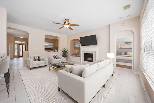 14402 Eastern Redbud Ln, Houston, TX 77044 - living area featuring light tile patterned floors, ceiling fan, a high end fireplace, and arched walkways