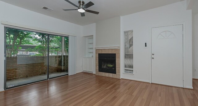 3500 Tangle Brush Dr Unit 217, The Woodlands, TX 77381 - unfurnished living room with wood finished floors, ceiling fan, built in shelves, a tiled fireplace, and baseboards