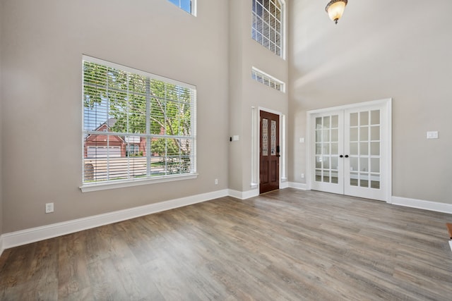 foyer entrance featuring french doors, healthy amount of natural light, wood finished floors, and a high ceiling