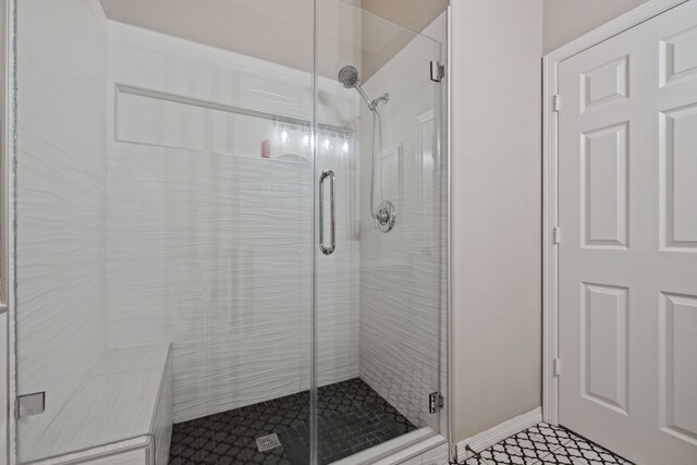 full bath with a stall shower, baseboards, and tile patterned flooring