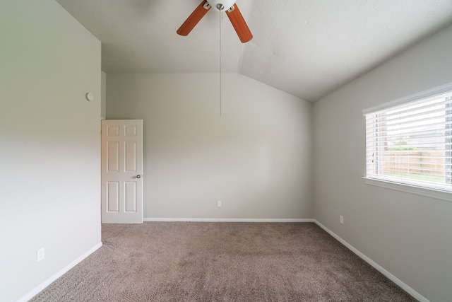 empty room with ceiling fan, vaulted ceiling, carpet flooring, and baseboards