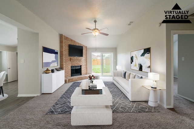 carpeted living area with lofted ceiling, ceiling fan, a brick fireplace, and baseboards
