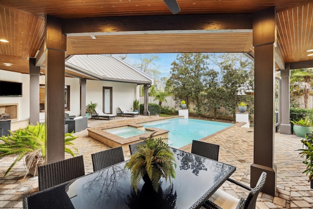 view of pool featuring outdoor dining area, a patio area, a ceiling fan, and an outdoor fireplace
