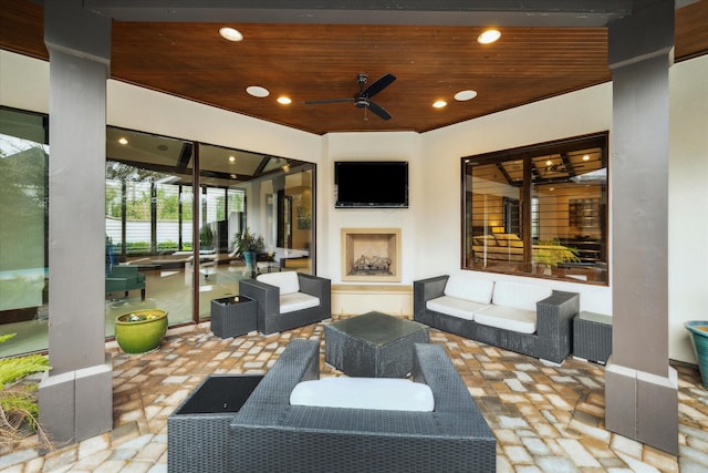 view of patio with an outdoor living space with a fireplace and a ceiling fan