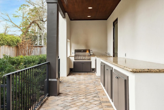 view of patio with grilling area, exterior kitchen, and fence