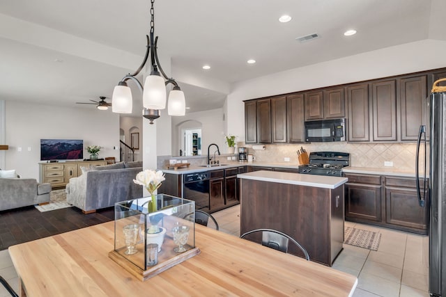 9962 Ash Creek Ct, Brookshire, TX 77423 - kitchen featuring black appliances, a sink, arched walkways, dark brown cabinetry, and decorative backsplash