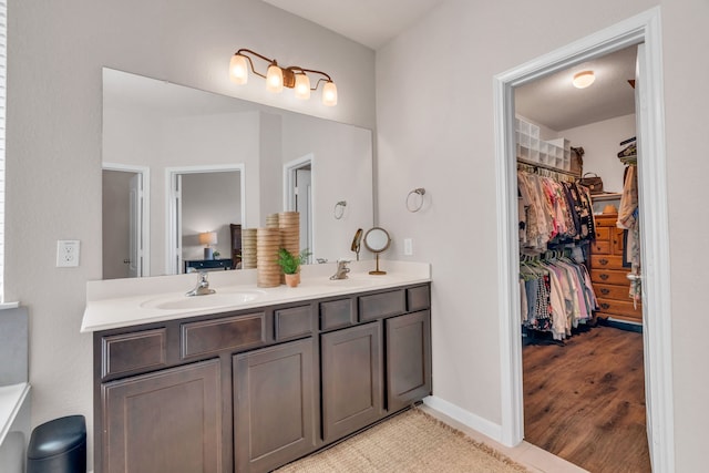 9962 Ash Creek Ct, Brookshire, TX 77423 - bathroom featuring double vanity, a spacious closet, and wood finished floors