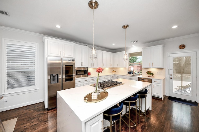 kitchen with stainless steel appliances, crown molding, a kitchen island, white cabinetry, and dark wood-style flooring