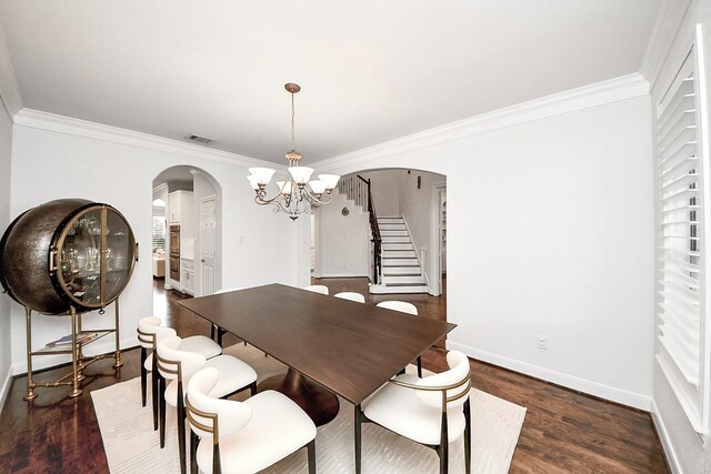 dining room with arched walkways, ornamental molding, a chandelier, baseboards, and wood finished floors