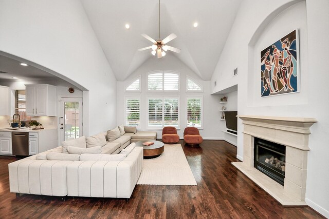 living room featuring ceiling fan, dark wood finished floors, a high end fireplace, high vaulted ceiling, and arched walkways
