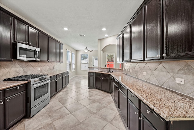 kitchen with appliances with stainless steel finishes, a sink, decorative backsplash, ceiling fan, and recessed lighting