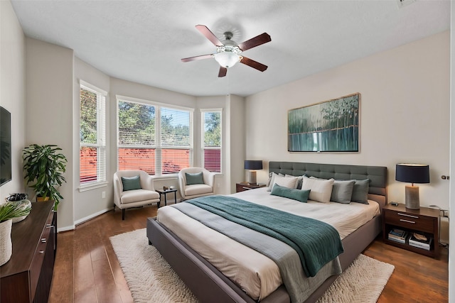 bedroom with dark wood-style flooring, ceiling fan, and baseboards