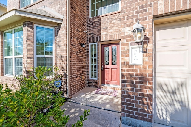 doorway to property with brick siding and a garage