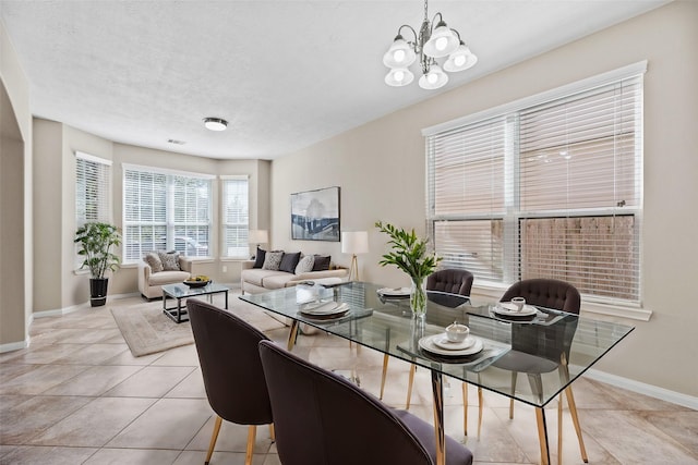 dining area featuring baseboards, a chandelier, light tile patterned floors, and a textured ceiling